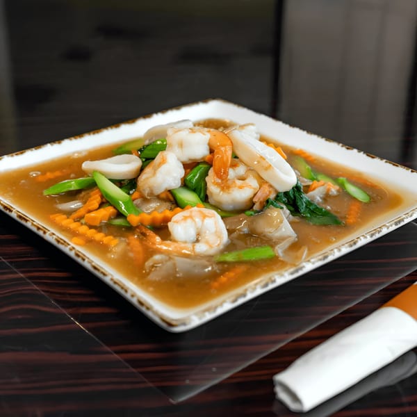 A Thai dish with shrimp, squid, carrots, and green vegetables in a savory brown sauce.