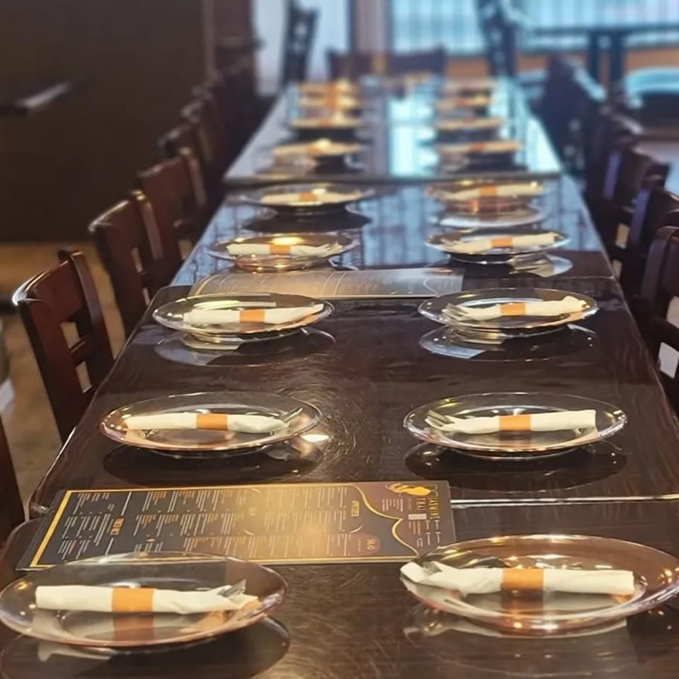 Long dining tables set with plates, rolled napkins, and menus at Jasmine Thai Restaurant.