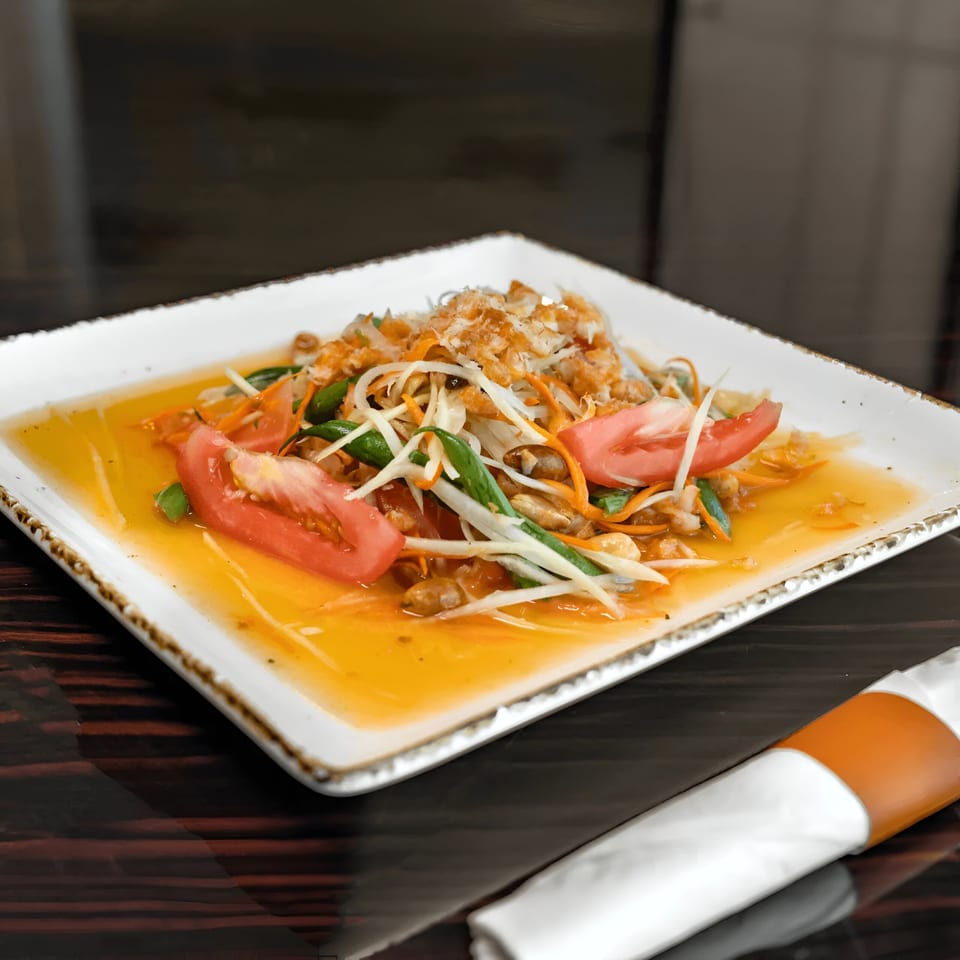 A vibrant Thai papaya salad with tomatoes, green beans, and peanuts in a tangy dressing.
