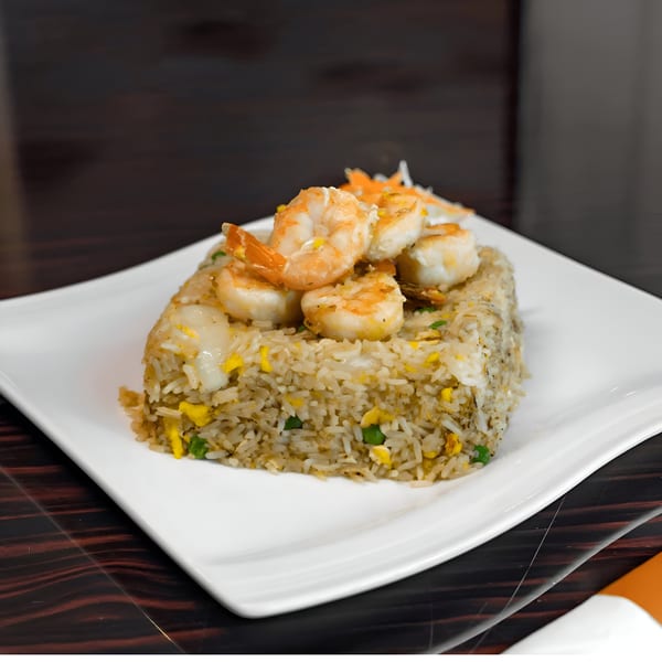 Shrimp fried rice with peas, egg, and carrots on a white rectangular plate.