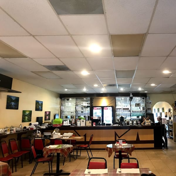 Interior of Jasmine Thai Restaurant with tables, chairs, a bar, and staff behind the counter.