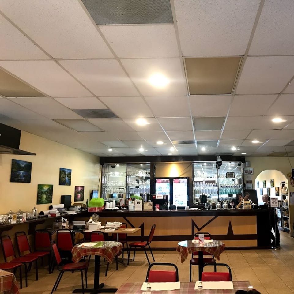 Interior of Jasmine Thai Restaurant with tables, chairs, a bar, and staff behind the counter.